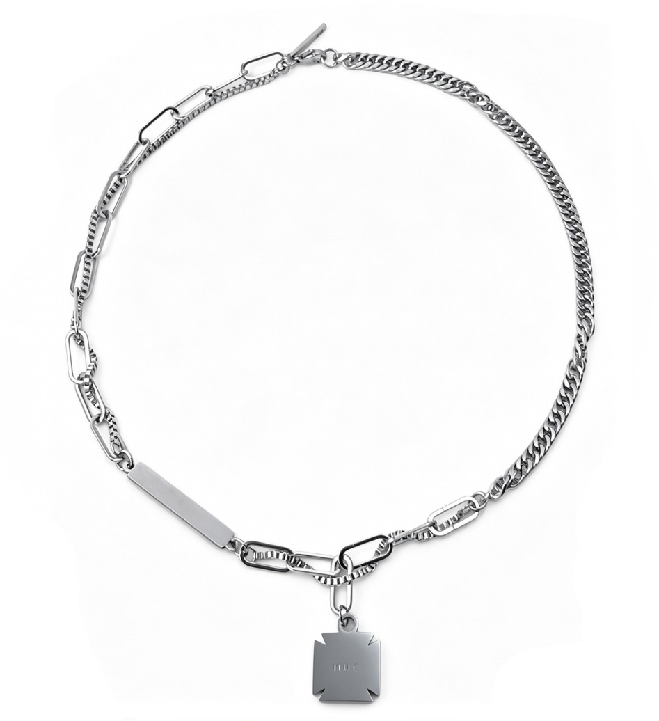Silver-tone asymmetric necklace mixing a curb chain and oval links with a flat bar and a cross-notched engraved tag pendant.
