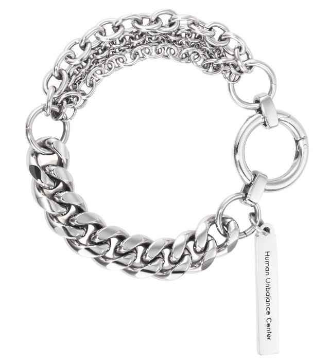 Silver-tone bracelet pairing a heavy curb chain with fine cable strands, an oversized ring clasp and a suspended engraved bar tag.