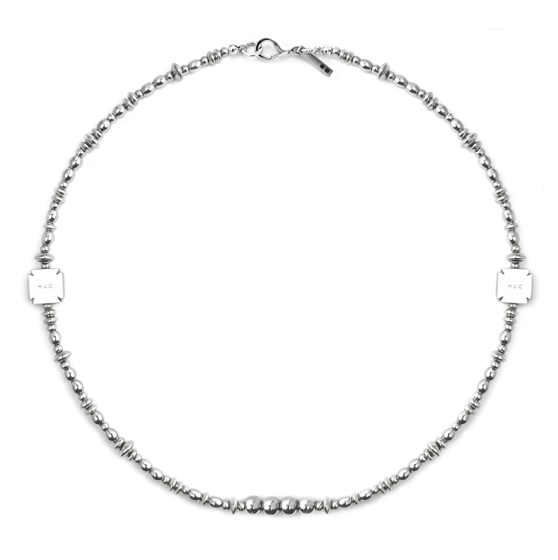 Silver-tone beaded necklace mixing round, olive, and saucer beads with two engraved square HUC plates and a hook-and-ring clasp.