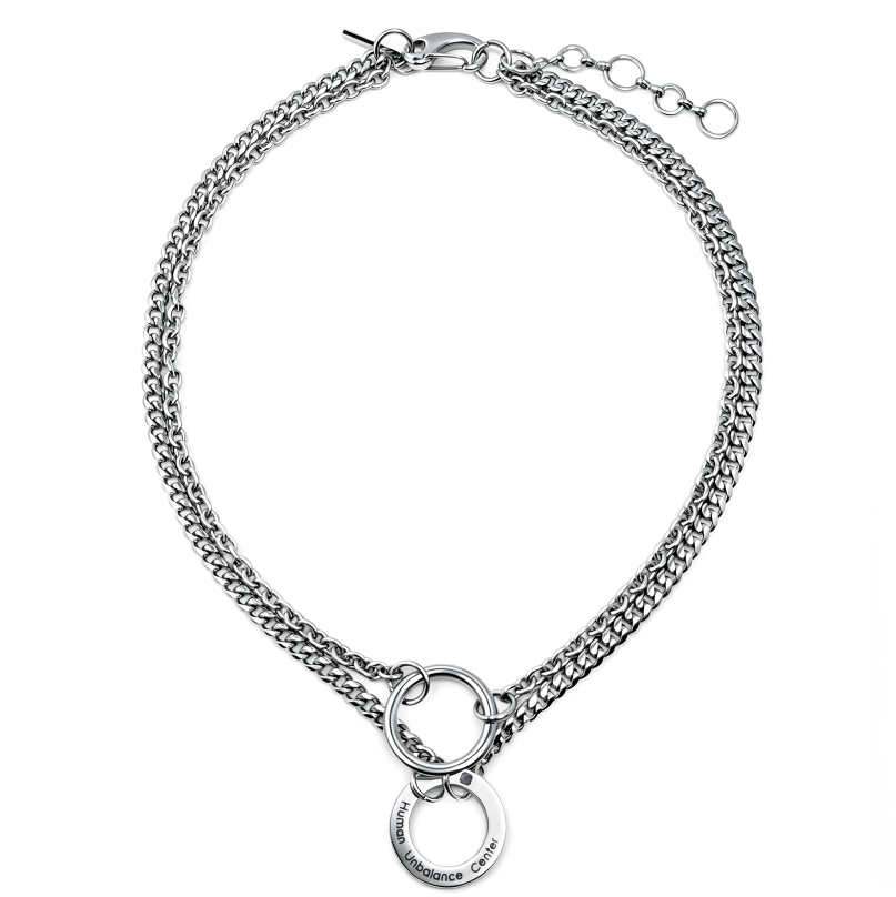Silver-tone double curb-chain necklace with a central polished ring and a suspended engraved circular tag.